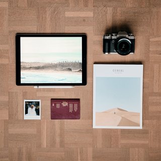 flatlay with camera, ipad, passport, polaroid and magazine